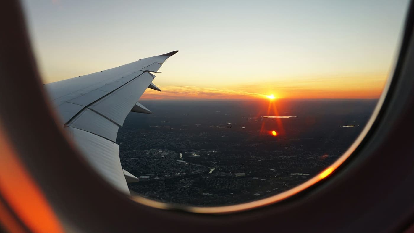 Blick aus dem Flugzeugfenster bei Sonnenuntergang – Anreise-Stimmung